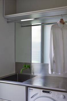 a washer and dryer in a room with clothes hanging on the rack next to it