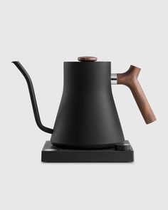 a black coffee pot with a wooden handle on a white background, the kettle is shaped like a teapot