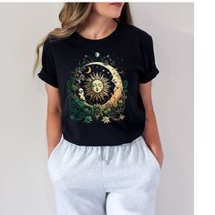 a woman wearing a black t - shirt with the sun and moon on it