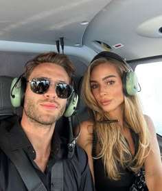 a man and woman sitting in the back seat of a car wearing headphones