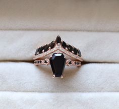 a black diamond ring sitting on top of a white velvet covered cushioned surface in a box