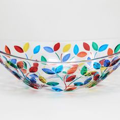 a glass bowl with colorful leaves painted on it