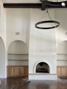 an empty living room with a fireplace and large clock hanging from it's ceiling