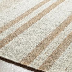 a close up view of a rug on a wooden floor with white and brown stripes