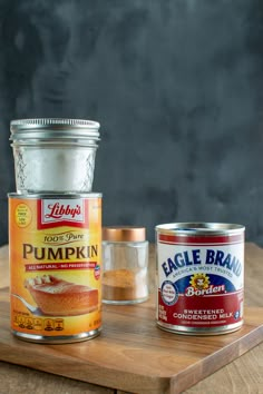 two cans of pumpkin spice on a cutting board next to an open can of pumpkin spice