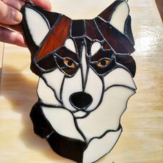 a hand is holding a stained glass wolf ornament