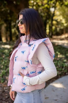 Light pink quilted puffer vest with ruffled shoulders and blue floral print Stay cozy and stylish in our Floral Trends pink puffer vest. This light pink vest features a playful blue floral print, ruffled shoulders, and convenient front pockets. Perfect for adding a pop of color to any outfit - show up, and show out! True to size fit; slightly cropped Model is 5'3" wearing a small Fabric doesn't contain stretch Zipper front closure Sleeveless with ruffle shoulders Front pockets Small length: 21" Cute Bonfire Outfits, Light Pink Vest, Bonfire Outfit, Bff Hoodies, Preppy Vest, Pink Puffer Vest, Trendy Vest, Puffer Vests, Germany Trip