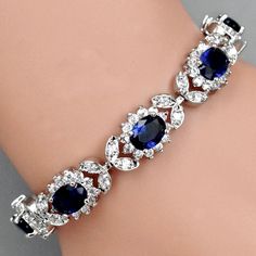 A beautiful piece of remarkable elegance, this exquisite bracelet will add a touch of sophistication to any wedding gown or formal ensemble. Adorned with flawless sapphire blue and clear cubic zirconia that capture the light from every angle with a perfectly translucent appeal, the bracelet is rhodium plated for a flawless finish which perfectly enhances the intricate detailing and conveys a modern take on old elegance. Length: 7.75" (approx. 19.6cm); Width: 0.5" (approx. 1.2cm). Closure is a se Blue Crystal Bangle Jewelry, Elegant Adjustable Blue Crystal Bracelet, Exquisite Wedding Tennis Bracelet With Cubic Zirconia, Blue Bangle Bracelet For Wedding, Blue Crystal Bracelets For Wedding, Blue Bangle Bracelets For Wedding, Sapphire Crystal Bracelet, Elegant Round Royal Blue Jewelry, Elegant Royal Blue Round Jewelry