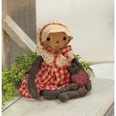 a small doll sitting on top of a wooden table next to a potted plant