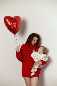 a woman holding a baby in her arms with a heart shaped balloon