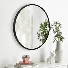 a white dresser topped with a mirror next to a potted plant