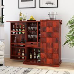 an entertainment center with liquor bottles and glasses on it in a living room next to a white chair