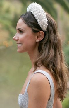 a woman wearing a white headband with pearls on it's hair and smiling