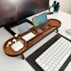 a computer desk with a cell phone, keyboard and mouse on it next to a monitor