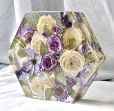 a glass vase filled with lots of flowers on top of a white bed coverlet