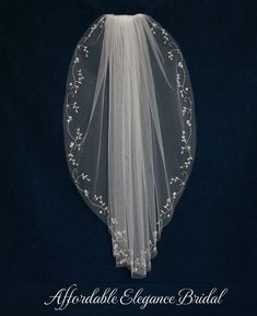 the back of a veil with flowers and leaves on it, against a dark background