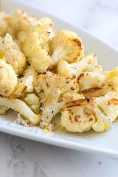 cauliflower on a white plate sitting on a marble counter top with seasoning