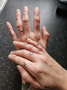 two hands with tattoos on them holding each other's fingers and touching their palms