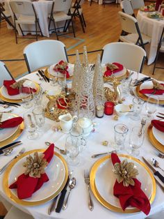 the table is set with white and gold plates, silverware, red napkins, and christmas decorations