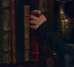 a person holding onto a book in front of a shelf with many books on it