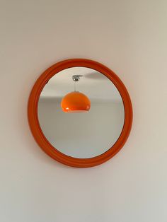 an orange circular mirror hanging on the wall