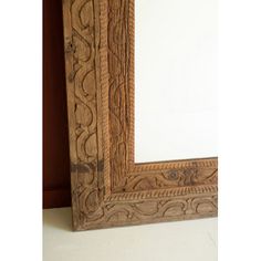 an old wooden frame with intricate carvings on the edges and sides, holding a large mirror