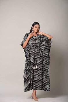 Pattern - Kaftan with dori & white Tassels Colour - Black background with gray and white print Print - Hand Block Printed Sleeves - 3/4th loose sleeves Neck design - V- neck Wash - Hand Washable Dress length - 52 inch Fabric - 100% Cotton Our Hand Block Print Blue Kaftan comes in a big and bold indigenous print with a delicate border design. The airy silhouette of the Kaftan gives you maximum comfort and makes this a very breathable attire. It features three-quarter sleeves. This easy-wearing Kaftan is perfect for any occasion, but you can also use it as a loungewear. Bohemian Kurta With Tassels For Eid, Bohemian Tasseled Kurta For Eid, Traditional White Kaftan With Tassels, Traditional Kaftan With Back Tassel Tie-up For Festivals, Traditional Festival Kaftan With Back Tassel Tie-up, Traditional Tassel Maxi Dress For Vacation, Traditional Vacation Maxi Dress With Tassels, Traditional White Dress With Back Tassel Tie-up, Traditional Kaftan With Tassels For Vacation