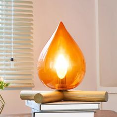 an orange light sitting on top of a stack of books next to a vase with flowers