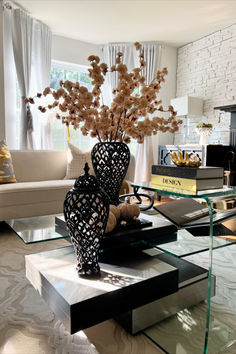 a living room with a glass coffee table and vase filled with flowers on top of it