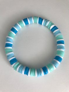 a close up of a bracelet on a white surface with blue and green strips around it