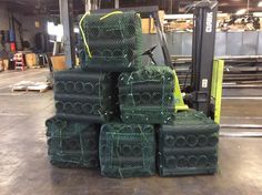 several green cages stacked on top of each other in front of a forklift and pallet