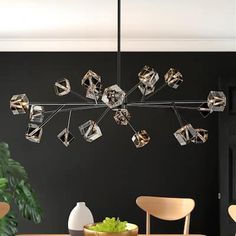 a modern chandelier hangs from the ceiling in a dining room with black walls