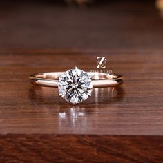 a close up of a diamond ring on a wooden surface with the words hello written below it