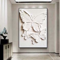 a large white butterfly sculpture in the middle of a room with two vases on either side