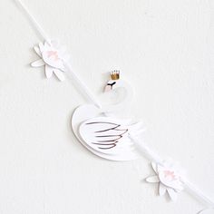 a white clock with pink flowers and a crown on it's head hanging from the ceiling