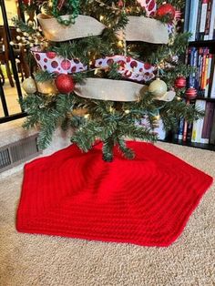 a red knitted christmas tree skirt sitting on top of a rug