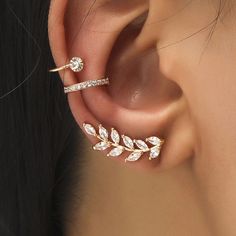 a woman's ear is adorned with gold leaves and crystal stones, while the rest of her ear is shown