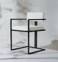 a black and white chair sitting on top of a white floor next to a wall