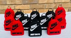 the nike backpacks are lined up on a white tablecloth with black and red logos