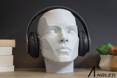 the head of a mannequin wearing headphones is next to books and a vase with flowers