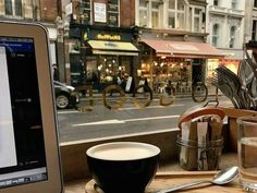 a laptop computer sitting on top of a wooden table next to a cup of coffee