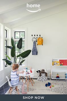 a child sitting at a table in front of a window with the amazon logo above it