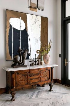 a large painting hanging on the wall above a wooden table with chess pieces and vases