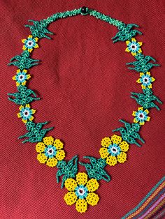 a beaded necklace with flowers and beads on it, sitting on a red cloth