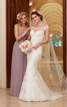 two women in dresses standing next to each other with veils over their heads and one woman