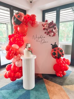 ladybug balloon arch with red and pink balloons on display in front of windows