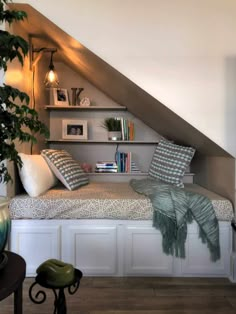 a bed sitting under a slanted ceiling next to a book shelf