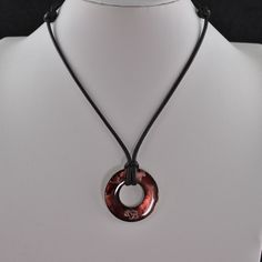 a necklace with a circular pendant hanging from it's side on a mannequin