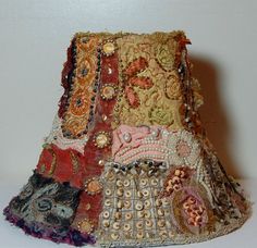 a lamp shade made out of old fabric and beadwork, with beads on the bottom