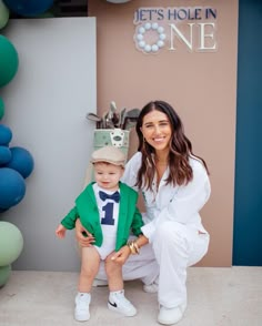 a woman kneeling down next to a little boy wearing a green suit and bow tie